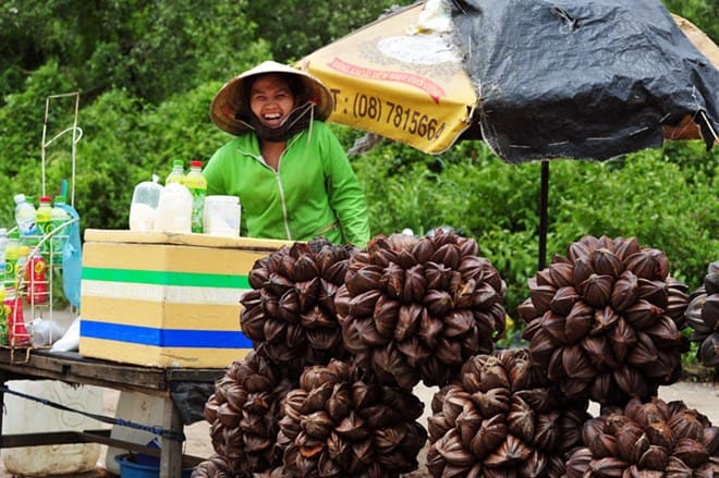 A smiling woman selling Dua Nuoc on the road from Can Gio to Sai Gon during a Ho Chi Minh City day trip