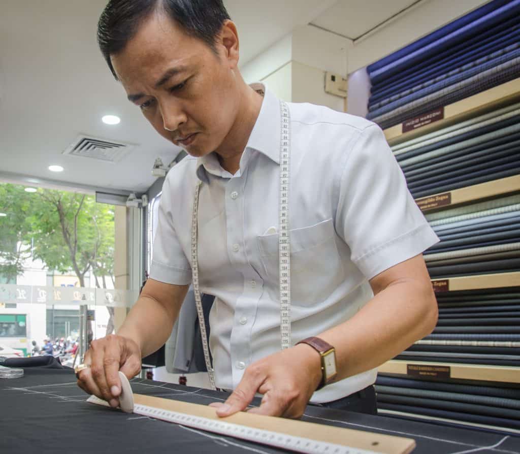 hoi an tailor measuring fabric